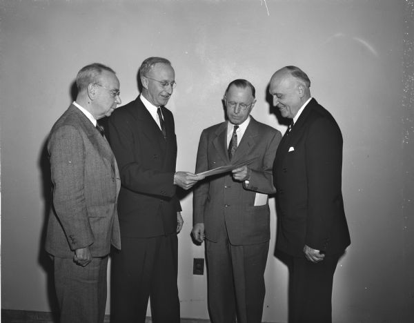 Forest Products Laboratory workers are honored in a ceremony. They received a silver superior service award in recognition of laboratory employees during World War II. Left to right: Carlile P. Winslow, formerly director of the Laboratory for nearly 30 years, Lyle F. Watts, U.S. Forest Service chief presenting the award to George M. Hunt, director of the Forest Products Laboratory, and President E.B. Fred of the University of Wisconsin.
