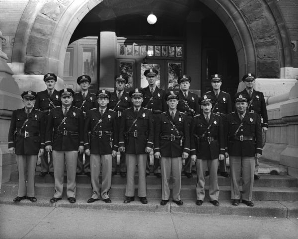 By 1934 the Dane County Highway Police staff had increased to four officers, was boosted to nine in 1937, and in three years to fifteen. The officers shown are Dane County Police members: front row, Lieutenant A.C. Pope, Officers Gerald Femrite, Ray Case, Rod Burgenske, Emil Schmale, Rodney Schwoegler, and Captain Larson; back row, Officers Russell Klitzman, E.W. Kelzenberg, Henry Gerry, Roland Brumm, Donald Harless, Robert Hickman, and Charles O'Brien.