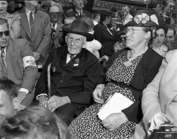 Lansing Wilcox, 102-years of age, the last surviving Wisconsin veteran of the Grand Army of the Republic, is seated in a crowd of people attending a Wisconsin Centennial event. Mr. Wilcox, from Cadott, Wisconsin, rode in the centennial parade.
