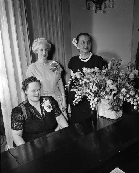 Three of the committee chairmen who helped with arrangements for the East Side Women's Club annual spring banquet. Seated at the piano is Mrs. Russell C. (Edith) Goodman, 1312 Williamson Street; standing is Mrs. Leo (Margaret) Kronenberg, 1439 Rutledge Street; and Mrs. Winfield (Ethel) Martin, 611 Elmside Boulevard.