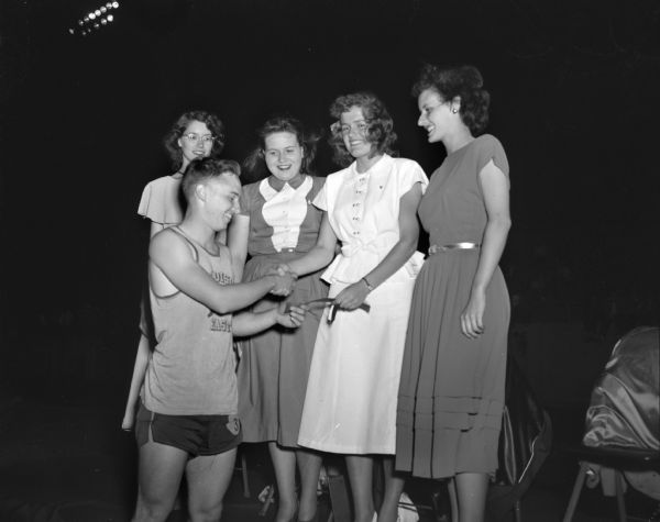 Members of the court of honor shown presenting an award to Radcliffe Sloggett, who set a new city record in the 100-yard dash in the city high school track meet at Breese Stevens Field. Members of the court are, left to right, Amelia Brueckner, Betty Neesvig, Elsa Oliversen, and Marguerite Michalson.