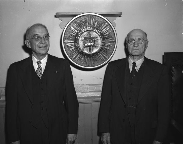 Anton J. Oelmiller, left, and John J. Scherer standing on either side of the Catholic Order of Foresters emblem. Oelmiller and Scherer were honored by St. Matthias court, Catholic Order of Foresters of Holy Redeemer parish, in recognition of their 50 years of membership.