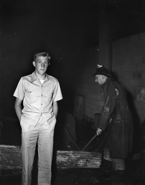 Donald Hanson, who discovered the fire at the lumber and appliance building of the Central Wisconsin Supply Company and turned in the alarm. The fire totally destroyed the building. A fireman with an ax is shown in the background.