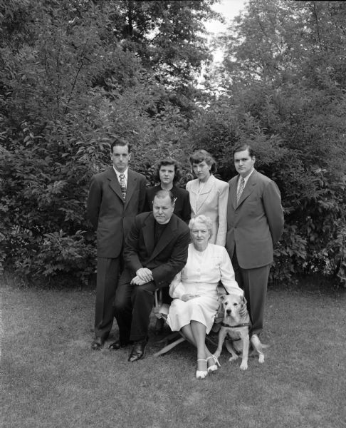 Group portrait of the Reverend and Mrs. Francis J. Bloodgood, former pastor of St. Andrews Episcopal Church and their family, taken at their home, 1102 Lincoln Street on graduation day. Seated in the foreground are Reverand and Mrs. Bloodgood. Standing left to right: Francis C. Bloodgood, twenty-four; Eve Bloodgood, seventeen; Jill Bloodgood, twenty, and Joseph W. Bloodgood, twenty-two. Francis, Jill and Joseph all graduated on the same day from the University of Wisconsin, where Eve is a student. The Reverend and Mrs. Bloodgood have also been attending classes at the university.
