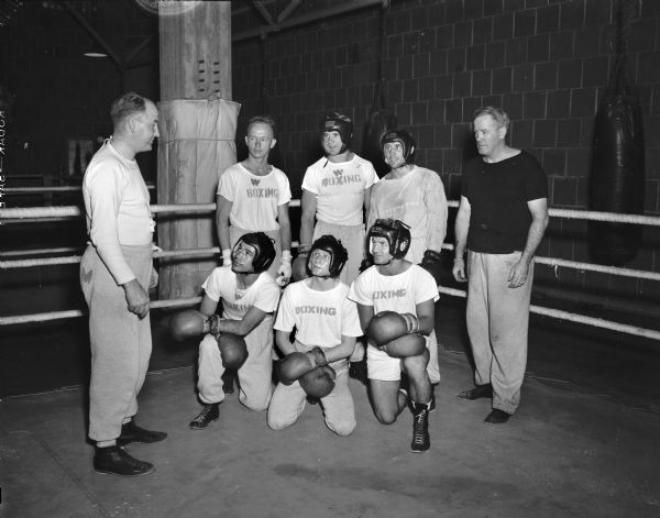 Group portrait of college champion boxers and coaches training for the Olympic trials at the University of Wisconsin-Madison. Pictured left to right: John J. Walsh, University of Wisconsin boxing coach; Charles Davey, Michigan State; Herb Carlson, University of Idaho; Don Dickinson, University of Wisconsin, and Vernon Woodward, assistant boxing coach. Front row left to right: Ernie Charbonaeu, Michigan State; Steve Gremban, University of Wisconsin, and Doug Ellwood, Louisiana State.
