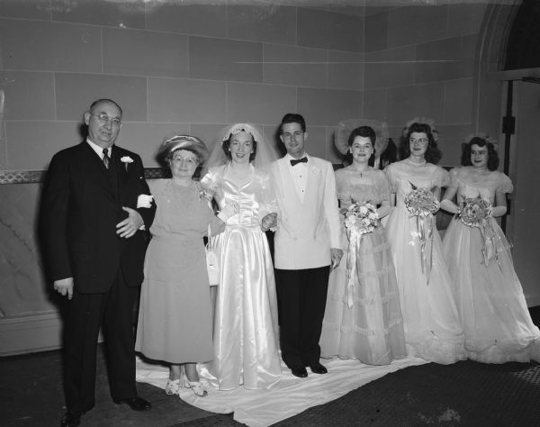 Group portrait of the wedding party of Rosemary Kathleen Plummer and Dr. Gordon Wilfred Newell, taken at St. Raphael's Cathedral. Left to right: the bride's parents, Mr. and Mrs. William F. Plummer, Sparta;  the groom, Dr. Newell, Madison; the bride, Rosemary Plummer Newell; maid of honor, Lois Mugan, Milwaukee; and bridesmaids Theresa and Margaret Mary Farrell, Milwaukee.