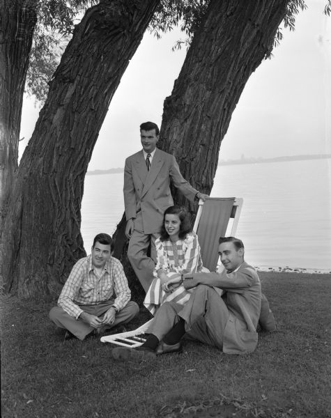 Posing outdoors on the shoreline of a lake are, left to right: Clem McCann, Thomas McGuire, Kathleen Kellogg and Robert Dunn, committee members of "The Assembly," a young people's dance club that sponsors benefit dances. Proceeds from the party will be divided between <i>The State Journal's</i> Empty Stocking club fund and <i>The Capital Times</i> Kiddie Camp rest home for rheumatic fever patients.
