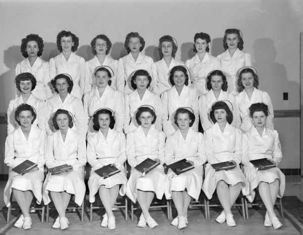 Group portrait of twenty-one young women who have just received their diplomas, marking their completion of a three-year basic course in nursing at St. Mary's School of Nursing.