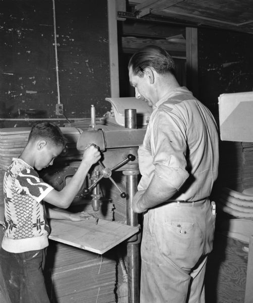 Joe Puccio, 13-year-old son of Mr. and Mrs. Lucian C. Puccio, working with a drill press in the shop of Henry Peiss to construct his soap box racer. The Nelson-Peiss Manufacturing Company is one of the business sponsors for the 1948 Soap Box Derby.