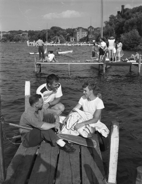 Seated on a Lake Mendota pier are left to right: Don Williams, Madison, a University of Wisconsin senior and member of Hoofers Club; Edward Bainbridge, commodore of the University of Michigan Yacht Club, and Paul Moore, Chicago, president of the Midwest Collegiate Yachting association.  Five universities that are members of the Midwestern Collegiate Yacht Association--Wisconsin, Michigan, Purdue, Ohio State and Denison--were in Madison to compete in the Hoofer invitational, one of the series of big regattas being held among colleges of the Midwest.
