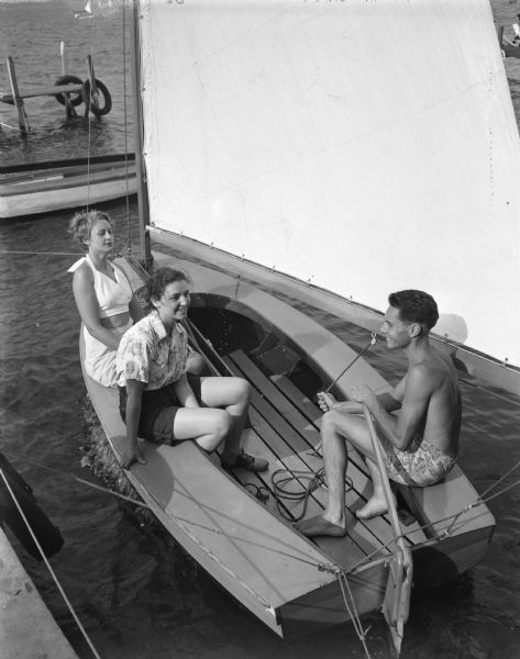 Phyllis Wentorf, West Bend, at left, and Pat Andrews, Madison, center--both members of the Hoofers Sailing Club--are pictured with Rudy Haase, Milwaukee, at right, in one of the two boats he and his brother, Roy, sail on Lake Mendota. Students from the five universities that are members of the Midwestern Collegiate Yacht Association--Wisconsin, Michigan, Purdue, Ohio State and Denison--were in Madison to compete in the Hoofer invitational, one of the series of big regattas being held among colleges of the Midwest.