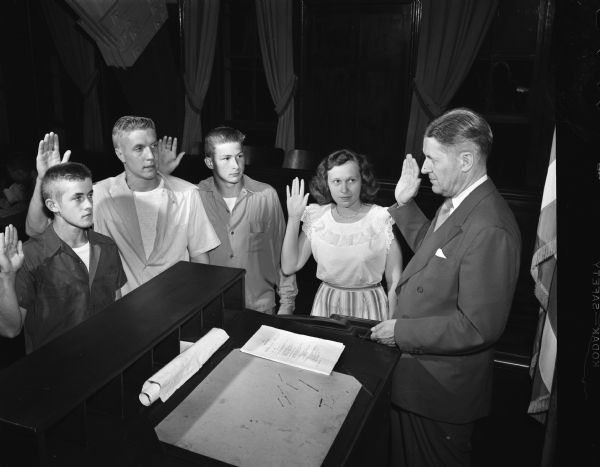 Group portrait of officers of the Madison Youth Council taking the oath of office. Pictured left to right: James Ketchum, son of Mr. and Mrs. L.W. Ketchum; George Steinmetz, son of Mr. and Mrs. George P. Steinmetz; Dick Roberts, son of Mr. and Mrs. V.B. Roberts; Jane Cleary, daughter of Mr. and Mrs. Ralph R. Cleary, and City Manager Leonard G. Howell.