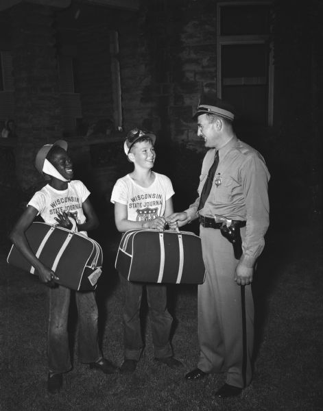 At right is Don Harless, Dane County traffic officer, presenting carry-all bags to winners of the sportsmanship award to Albert Martin, son of Mrs. Annabelle Martin, 19 South Murray Street, and Billy Morrison, son of Dr. and Mrs. Mariott Morrison, Mt. Horeb,