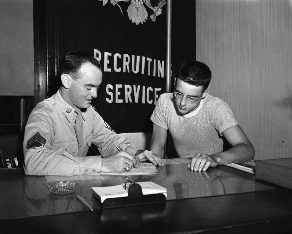 Staff Sgt. John C. Ludden, U.S. Air Force, filling out enlistment papers for his brother, James G. Ludden, 17, a 1948 graduate of East High School, at the U.S. Army and Air Force Recruiting station, 103 West Main Street.