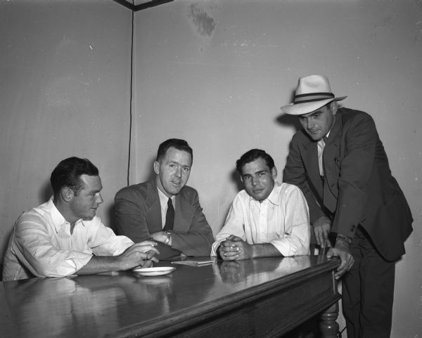 Madison detectives quiz two men who have confessed to having committed fifteen burglaries in the Madison area. Left to right: Vann Millege Kidd, Texarkana, Texas; Detective A.T. Nygaard; Raymond G. "Tex" Galbraith, Madison County, Indiana, and Detective Elroy Beckman. The two felons are known as the "night hawk" burglars.