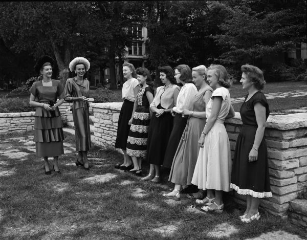 On the left are co-ed models, Gale Turnbull, New Bern, North Carolina, and Millicent Jakovich, 1846 Jenifer Street, who display new fall styles to seven of the committee chairmen who are arranging the fashion show. They are, left to right: Louise Miller, South Milwaukee; Marilyn Miller, Milwaukee; Charlotte Siker, 508 E. Gorham Street; Anita Dahlke, Princeton; Mary Olberg, La Crosse; Patricia Johnson, La Crosse and Faye Sivula, Ironwood, Michigan.