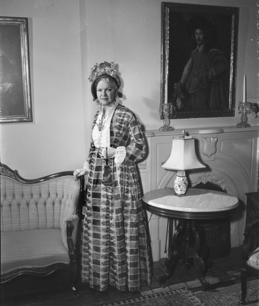 Mary Rennebohm, wife of Governor Oscar Rennebohm, is shown dressed in a nineteenth century gown and bonnet while serving as a hostess at the opening day of the Women's Building at the Centennial Exposition. The gown, fashioned of heavy plaid silk in muted tones of grey and lavender, was worn in 1850 by Mrs. L.M. Hank's paternal grandmother, Mrs. Levi Baker Vilas, who was married in Vermont in 1838. Mrs. Vilas, who had eight sons and one daughter, lived on North Henry Street, when her home was the only house in the area.