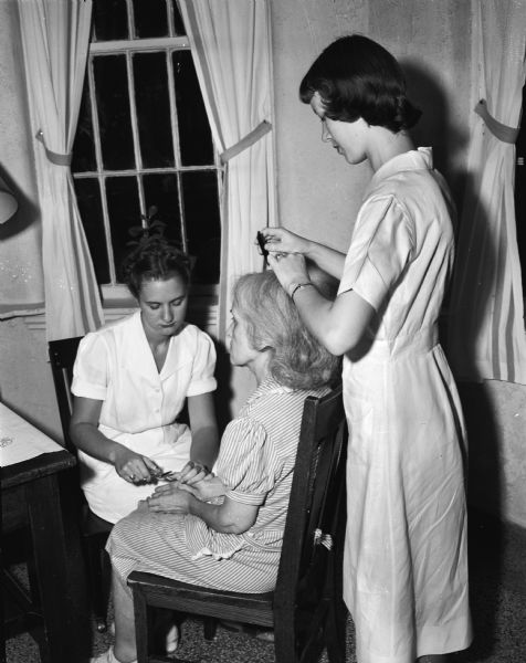 A Mendota State Hospital patient shown having her hair arranged and nails manicured by Lucille Schultz (left) from Manitowoc, a University of Wisconsin student, and Miriam Jespersen from Sycamore, a Beloit College student, standing. (Mendota Mental Health Institute)