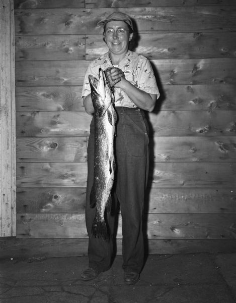 Mrs. Arthur O. (Cecelia) Johnson holding up a 38-1/2 inch northern pike, which she caught in Lake Mendota near Spring Harbor.