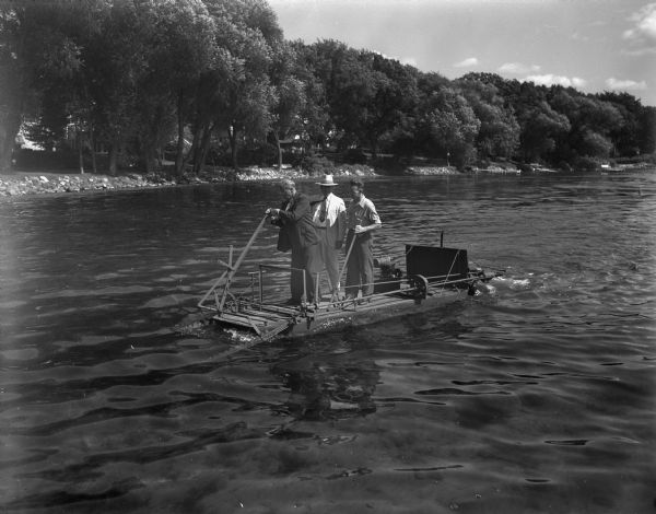 W.J. Rendall, Earl. E. Wheeler, and George C. Hockney operating a small weed cutter in Lake Mendota off the shore of Maple Bluff. Mr. Hockney is the manufacturer of the underwater cutter.