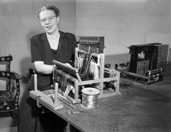 Mrs. Wilfred J. (Ruth) Harris, Lake Mendota Drive, is shown weaving a purse on a small loom.