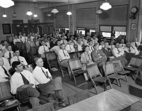 Men and women seated in the audience at a paper mills meeting.