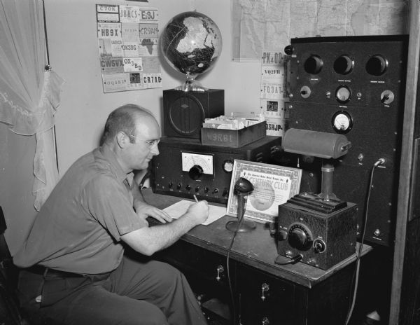 Ross Hansch, 1608 Hoyt Street, Ham Radio Operator (W9RBI), Wisconsin's first member of the DX Century Club. The club is limited to amateur radio operators who have made verified radio contacts with 100 or more other countries since the end of World War II. He is seated with his radios.