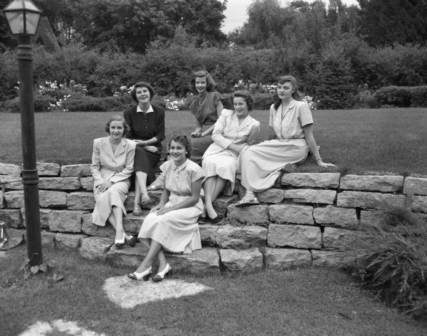 Six Madison co-eds sitting on a stone retaining wall. All will be attending Stephens College in Columbia, Missouri. Pictured from the left are:  Patricia Rowlands, Patricia Clardy, Mary Carol Blume, Jean Dudley, Sally Bixby, and Rosemary Watson.
