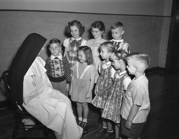 Sister Mary Flora of St. Raphael's School greets eight newcomers to the school. The new first graders are, front row, left to right, Michael Maloney, Elizabeth Jane McGilligan, twins Jo Anne and Jean Elvert, and Jimmy Mueller. In the second row, left to right, are Margaret Mary Cawley, Margaret Gill, and Ralph Malec.