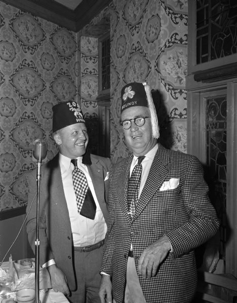 Ralph Olson, left, a member of the governing body of Zor Shrine, presenting Roundy Coughlin with a special Kelly green fez as a token of appreciation for his work in their fund drives.