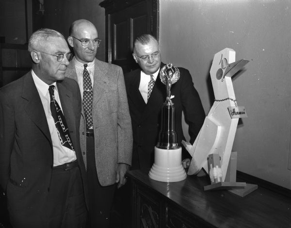 Three officials of the Madison Community Chest drive shown examining two awards at the "kick-off" meeting for the advance gifts division. At left is Theron Brown, vice-president of Madison Gas and Electric Company and chairman of the public service section. In the center is Oscar G. Mayer, Jr., operations manager of Oscar Mayer and Company and chairman of the manufacturing and construction section. At right is Alan C. Hackworthy, vice-president of Robert W. Baird Investment Company and general chairman of the advance gifts division.