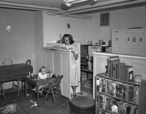 Mrs. Theodore Statz and her 6-month old daughter Cindy in the kitchen of their basement apartment at 425 West Wilson Street. They are soon to be evicted because their apartment does not meet building code limitations.