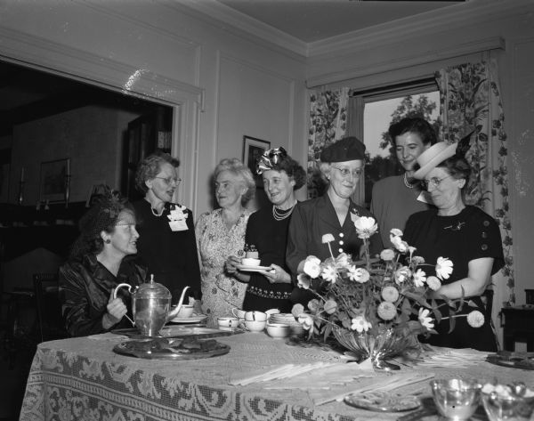 Seven members of the Madison chapter of the League of Women Voters at their annual fall tea at the home of Mrs. Stanley (Myrtle) O'Shea.  Pictured from left to right are: Mrs. Austin T. (Daisy D.) Breyer pouring tea, Mrs. O'Shea, Mrs. Ralph F. (Mildred J.) Norris, Mrs. Kenneth G. (Rachael M.) Shiels, Mrs. A.S. (Dolores) Baer, Miss Emily Dodge, and Mrs. Frank L. (Berta) Clapp.