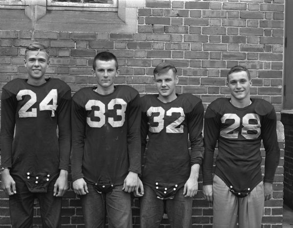 Four Madison East High School football players posing outdoors in uniform.