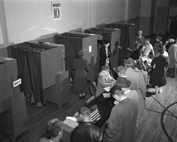 Elevated view of a crowd of voters and five curtained voting machines at Ward 10.