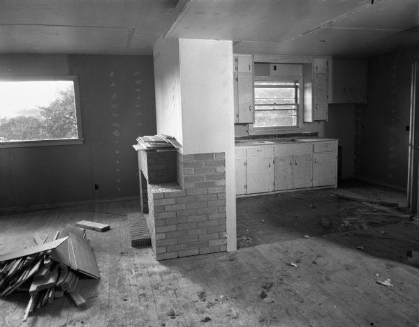 Interior of a low cost house being constructed for sale to veterans of World War II by builder Marshall Erdman. The project of four houses is being constructed on Midvale Boulevard in Sunset Village on Madison's West Side. The living room, at left, is divided from the kitchen and dining area, at right, by a partition and a fireplace.