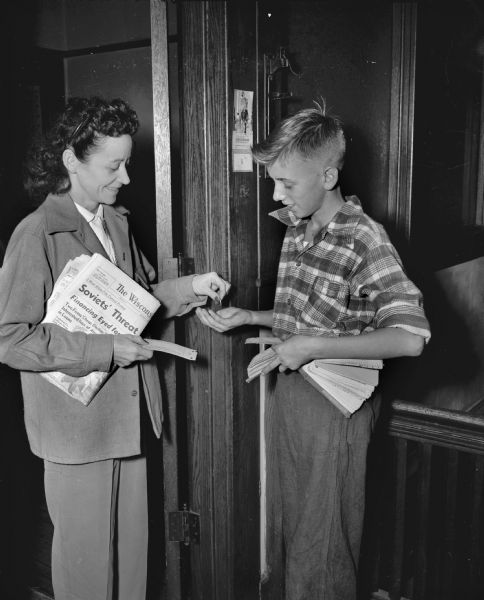 Ronnie Hinrichs, a recently hired newspaperboy for the <i>Wisconsin State Journal</i>, is shown as he delivers the paper to a customer, Mrs. Ida Mealy, and collects for the week.