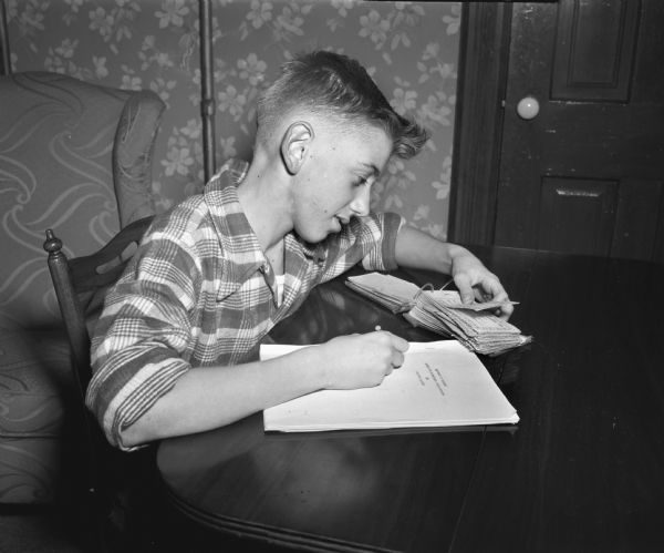 Ronnie Hinrichs, a recently hired newspaperboy for the <i>Wisconsin State Journal</i>, performing the bookkeeping for his account.