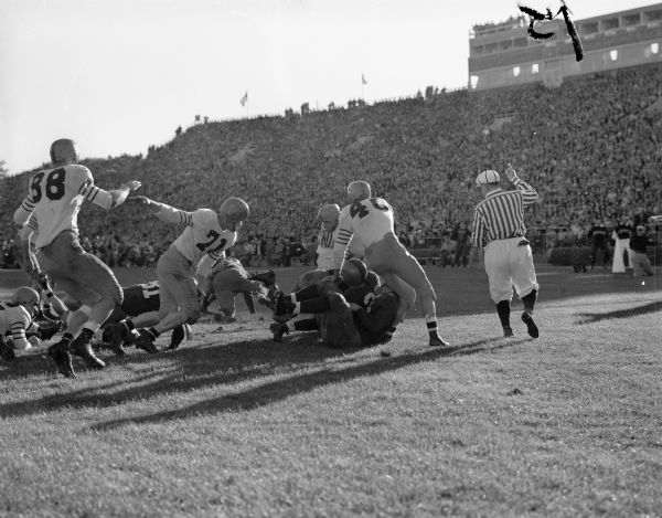 Clarence Self (18) scores the winning touchdown against Illinois as the University of Wisconsin beat Illinois 20 to 6 at Camp Randall Stadium. Other Wisconsin players in the picture are fullback Bob Radcliffe (32) and quarterback Lisle Blackbourn, Jr. (26).