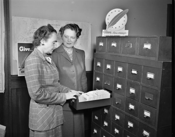 Mrs. Jerome H. (Helen) Coe and Mrs. Wayne K. Loveland, who are two members of the Madison Community Chest campaign headquarters staff, shown at the office files.