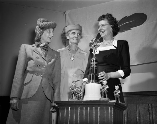 Three division chairmen view the trophy that will be awarded to the division that attains the highest percentage of its quota for the Madison Community Chest campaign. Shown are Mrs. W.C. (Emma) Sieker and Mrs. C.V. (Eva) Sutcliffe.