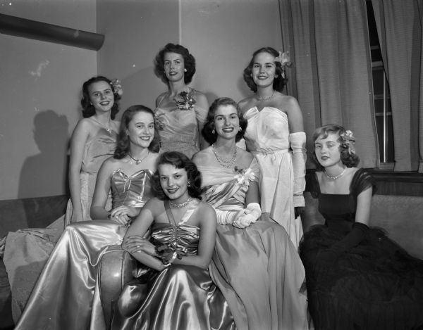 Portrait of seven University of Wisconsin co-eds dressed in formals. They composed the court of honor for the Wisconsin State Centennial Ball held at the Memorial Union and sponsored by the University. Co-eds include Lenore Ladewig, Milwaukee, Wisconsin; Carolyn Royce, Savannah, Georgia; Carol Erdman, Manitowoc, Wisconsin; Mary Lou Behrens, Stanley, Wisconsin; Rosemarie Schneiders, Madison; Joan Henderson, Highland Park, Illinois; and Virginia Rowlands, Cambria, Wisconsin.