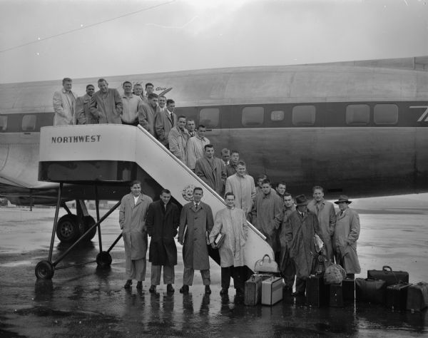 The University of Wisconsin football team shown boarding an airplane at Truax Field for a trip to Oakland, California, to play the University of California.