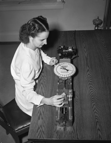 University of Wisconsin home economics graduate student Louise Page, Payson, Utah, using a meat tenderness machine to test a sample of meat.