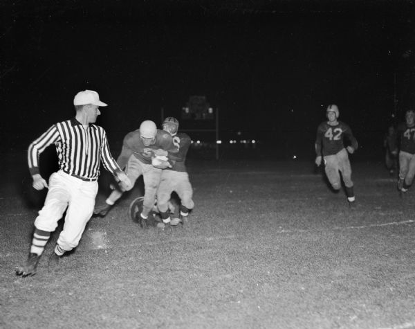 Racine Park's Charles Henkel, 215 lbs., is shown smashing his way to a good gain off tackle. Gene Blanchar is having trouble bringing him down. East defeated Racine Park 7-6 in the Pageant Night feature at Breese Stevens Field.