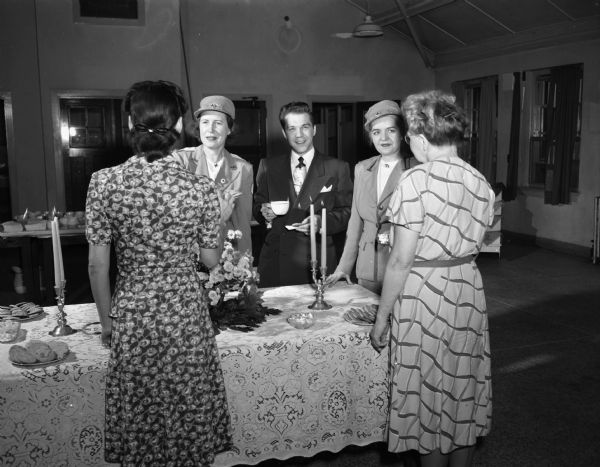 Gray Ladies of the Dane County Red Cross serving tea to two unidentified patients at the Mendota hospital for the mentally ill. Left to right are: Mrs. H. Lewis Greene, chairperson of the Gray Lady service; pianist Joey Ray, who came out to entertain the guests; and  Mrs. Vern S. Bell, chairperson of volunteer services for the county chapter.