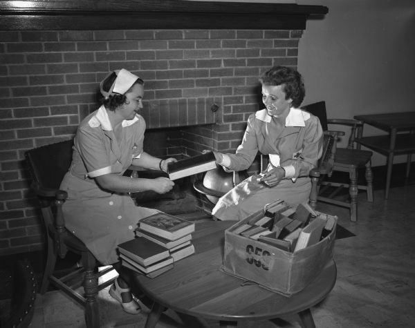 Gray Ladies of the Dane County Red Cross sorting books at the library of Mendota hospital for the mentally ill. Left to right: Mrs. Frederick Hillyer, and Mrs. William Murray.
