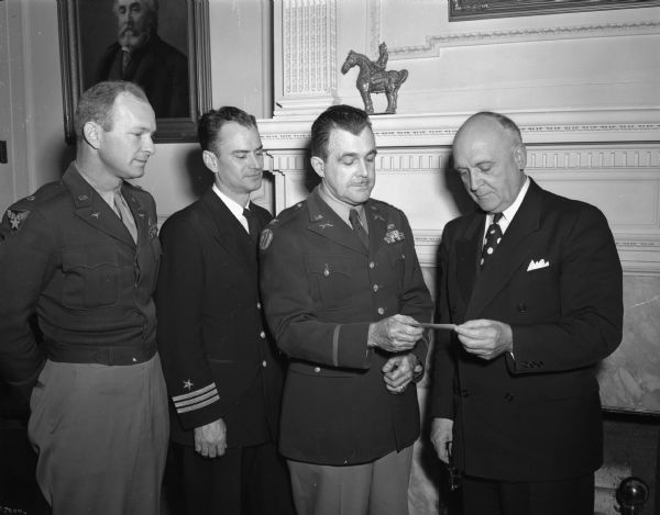 Edwin B. Fred, president of the University of Wisconsin, accepting an invitation to a reception being planned in his honor by army, navy and air force officers assigned to active duty on the Madison campus. Pictured left to right: Lieutenant Glenn A. Stell, associate professor of military science and tactics; Commander Ralph M. Metcalf, associate professor of naval science; Colonel Carl E. Lundquist, professor of military science and tactics; and President Fred.