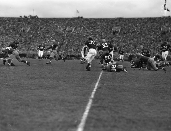 University of Wisconsin football player Ben Bendick being tackled during the Wisconsin-Northwestern homecoming game. On the ground in the foreground is Wisconsin quarterback Lisle Blackbourn, Jr.