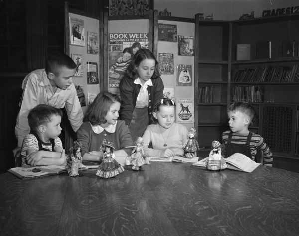 Six children preview new books and historical dolls. Left to right they are: James Scrivner, Paul Ives, Shirley Kleven, Carolyn Watzke, Judy Kay Lemon and Danny Stiehl.